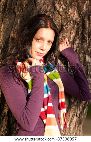 Winter outfit portrait of beautiful female model posing by tree bark