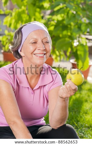 Senior sportive woman smiling eat apple outdoor sunny day