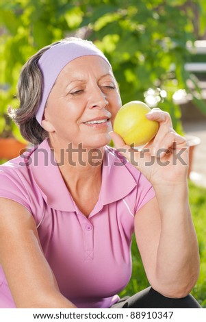 Senior sportive woman smiling eat apple outdoor sunny day
