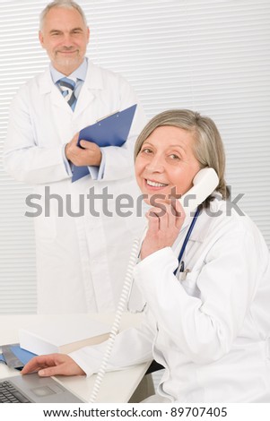 Medical senior doctor female calling with professional male colleague office