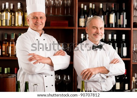 At the bar - happy barman and chef standing cross arms