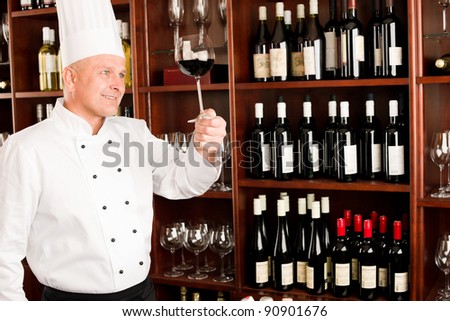 Chef cook hold glass of red wine in restaurant bar