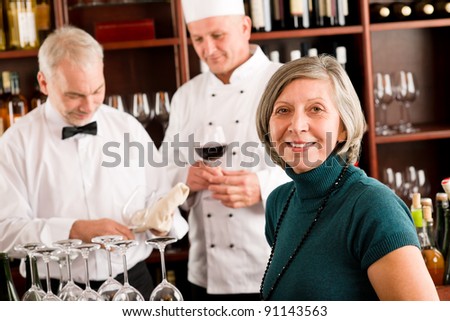 Restaurant manager smiling with staff at wine bar