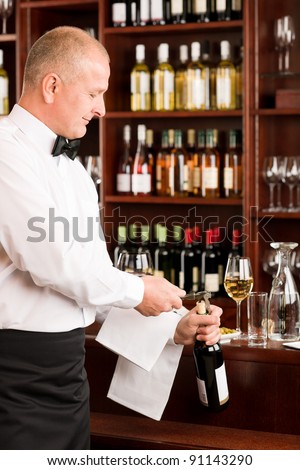 Wine bar professional waiter mature opening bottle in restaurant
