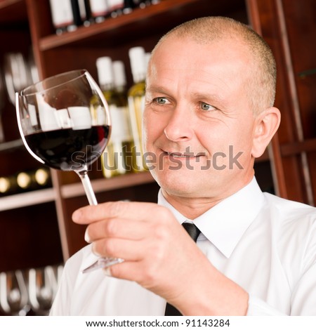 Waiter at bar hold glass of red wine in restaurant