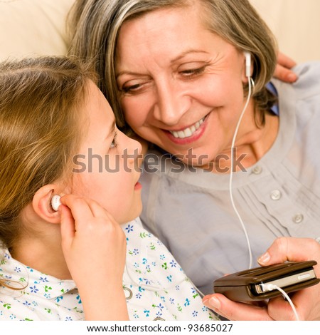 Granddaughter and grandmother listen to mp3 music headphones together smiling