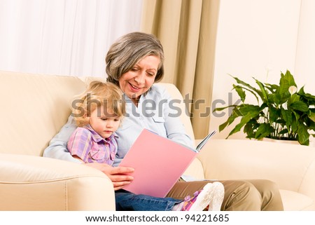 Grandmother and little girl reading book happy together at home