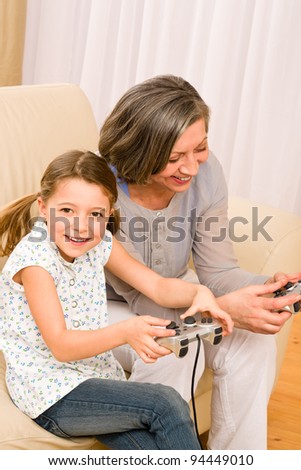 Grandmother play computer game with enthusiastic young girl have fun smiling
