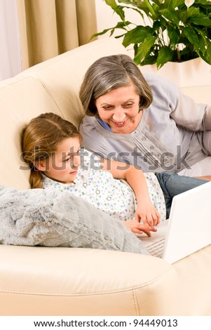 Grandmother with young girl use computer laptop happy together
