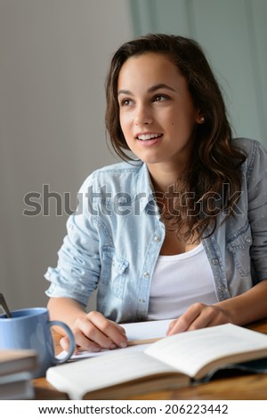Teenage student girl looking away studying at home