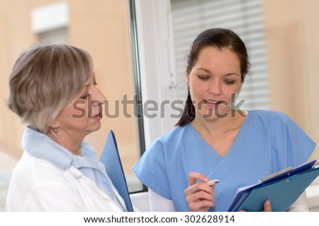 Two female doctors in hospital looking at patient files
