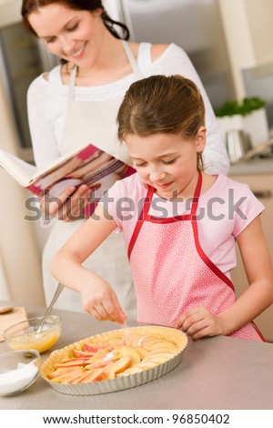Young girl prepare home tart with mother adding sugar