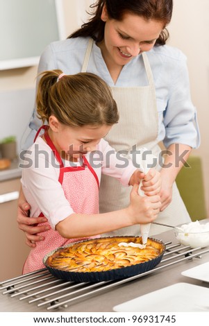 Mother and daughter decorating apple pie with whipped cream