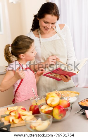 Apple pie mother and daughter follow recipe from baking cookbook Apple pie mother and daughter follow recipe from baking cookbook