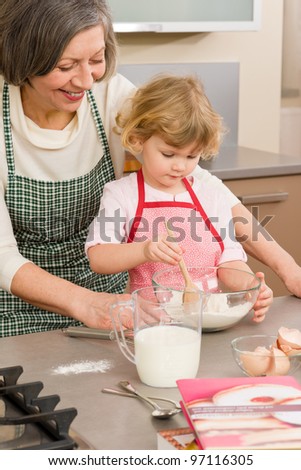 Child girl and grandmother baking cake stir flour