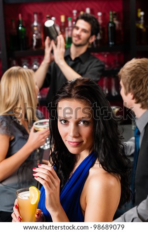 Smiling woman having drink with friends at cocktail bar