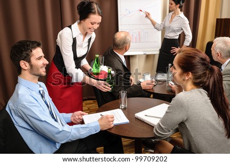 Waitress serving people at business meeting flip-chart presentation