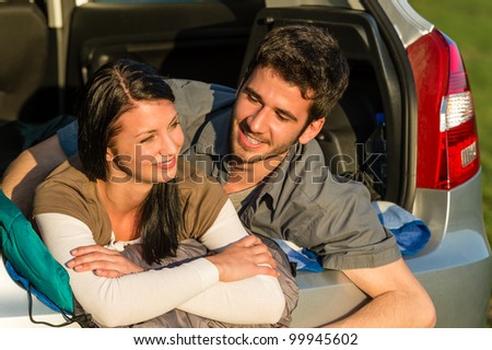 Camping young couple hugging together in car summer sunset