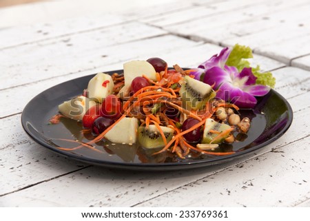 Mixed fruit salad thai style. Colorful fruit salad closeup.On white wood table.