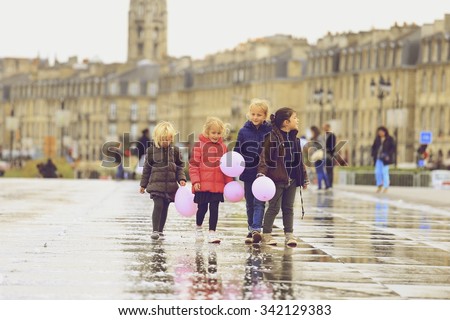 BORDEAUX, FRANCE - 15 November, 2015 : Group of girls with pink balloons walking on Bordeaux water mirroring autumn, the pool is the largest water mirror in the world with 3450 sq.m.