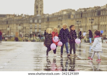 BORDEAUX, FRANCE - 15 November, 2015 : Group of girls with pink balloons walking on Bordeaux water mirroring autumn, the pool is the largest water mirror in the world with 3450 sq.m.