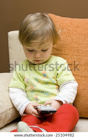 baby girl with remote control on  sofa