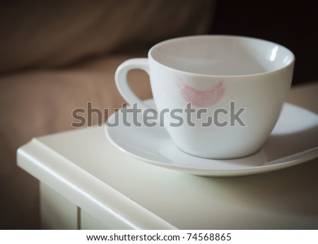 coffee cup with a lipstick mark on rim on a bedside table