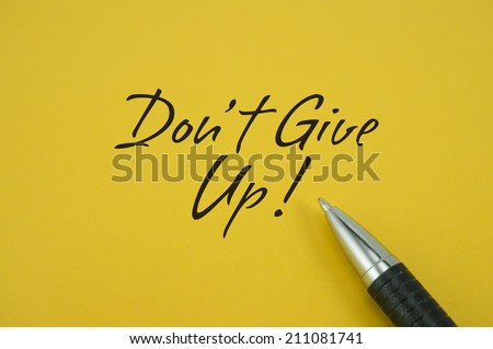 Don't Give Up! note with pen on yellow background