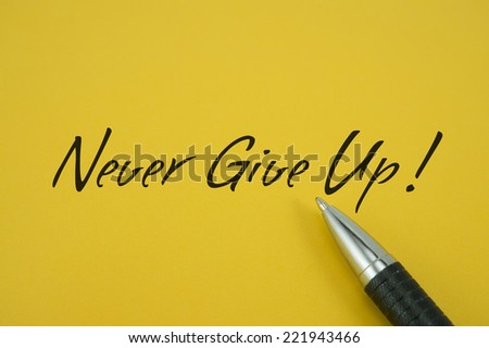 Never Give Up! note with pen on yellow background