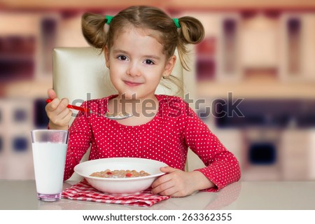 Little girl have a meal home. Kid healthy food. Smiling child eats snack with milk.