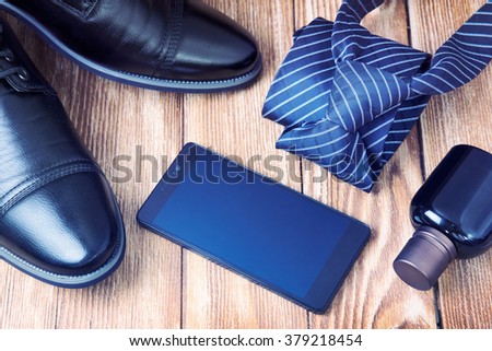 Happy father\'s day.Men\'s fashion accessories:shoes,tie,perfume,mobile phone empty screen background.Male items on wooden background space for text message.Retro lifestile set.