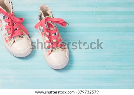 Journey travel concept.Child\'s female kid\'s textile sneakers shoes on blue wooden background empty space for text.