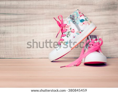 Child\'s textile sneakers white lace shoes on wooden floor background empty space.Childhood concept wallpaper.Kid\'s apparel.