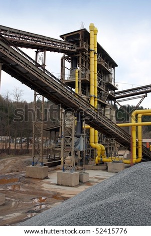 Stone quarry with silos, conveyor belts and piles of stones.