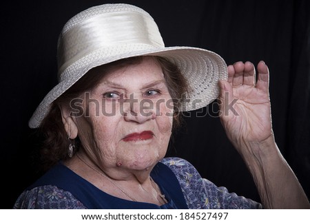 Portrait of the old woman in a hat on a black background