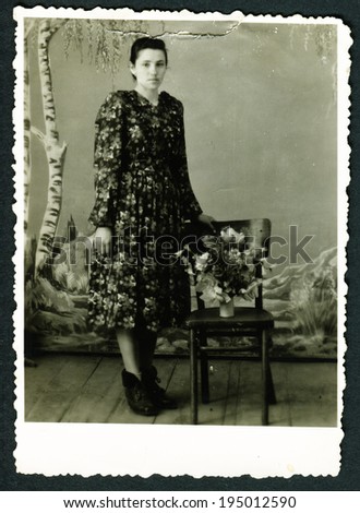 USSR - CIRCA 1970s: An antique photo shows studio portrait of a woman near the chair with flowers, USSR, circa 1970s