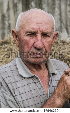 portrait of a sad old man on a straw background