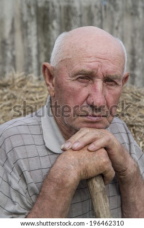 portrait of a sad old man on a straw background