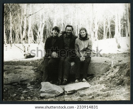 USSR - CIRCA 1970s: An antique photo shows man and two women sitting on a rock in the forest