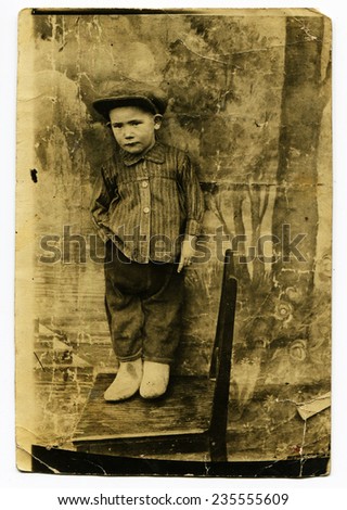 Ussr - CIRCA 1930s: An antique Black & White photo show little boy in a cap standing on a chair