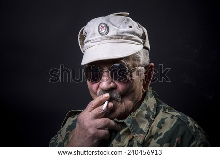 old man in sunglasses and camouflage smokes a cigarette