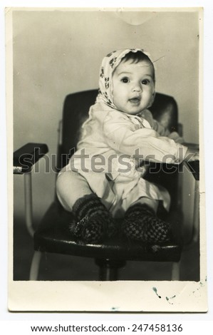 Ussr - CIRCA 1980s: An antique Black & White photo show girl in a scarf sits on a chair