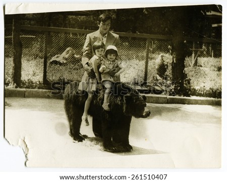 USSR - CIRCA 1970s: An antique photo shows father and two little girls on a stuffed bear