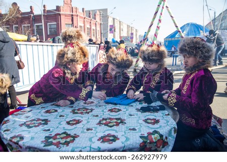 PETROPAVLOVSK, KAZAKHSTAN - MARCH 21, 2015: celebration of the new year on the solar calendar astronomical in Iranian and Turkic peoples. Boys in traditional costumes playing Togyz Kumalak