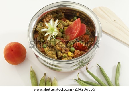 Mix vegetable in steel pot with raw vegetables on white background.