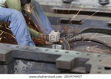 Industrial worker grinding metal with many sharp sparks
