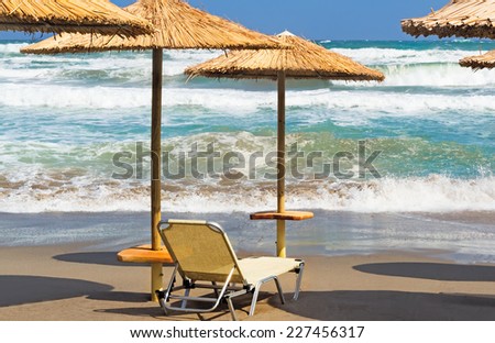 Land sea beach with umbrellas and loungers on the background of a stormy sea.