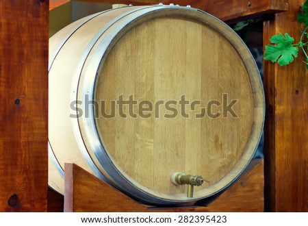 Large durable , made of natural oak, barrel for wine with a metal crane, is located on a convenient wooden stand.