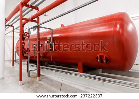Industrial big red tank inside factory. Tank for water under high pressure. Fire systems.
