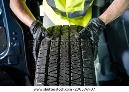 Car Tire Replacement. Tire Service. Men with Brand New Tire is Ready For Installation.